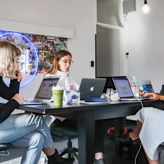 A group of people sitting at a table with laptops.