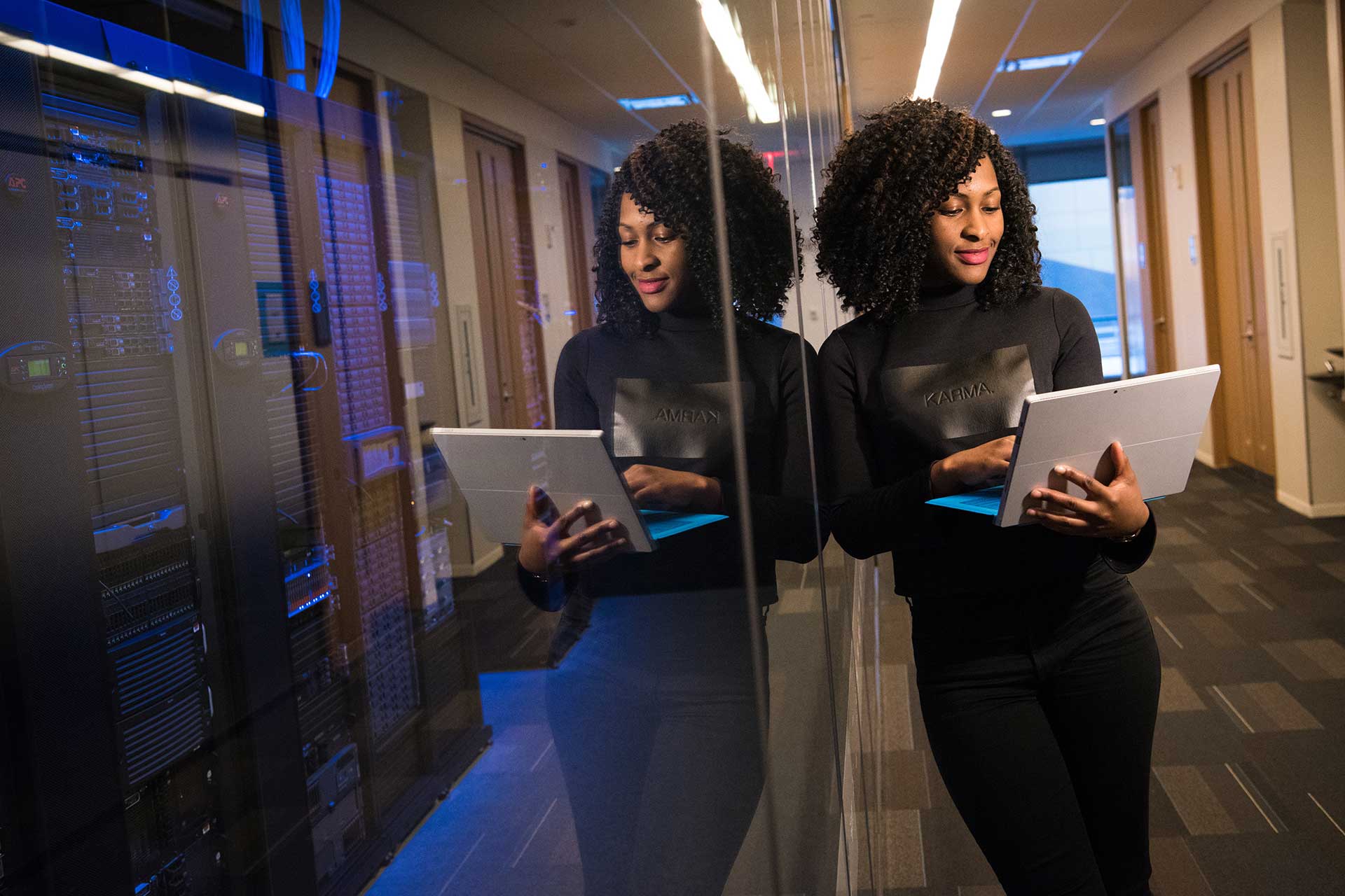 A woman is holding her tablet in front of a mirror.