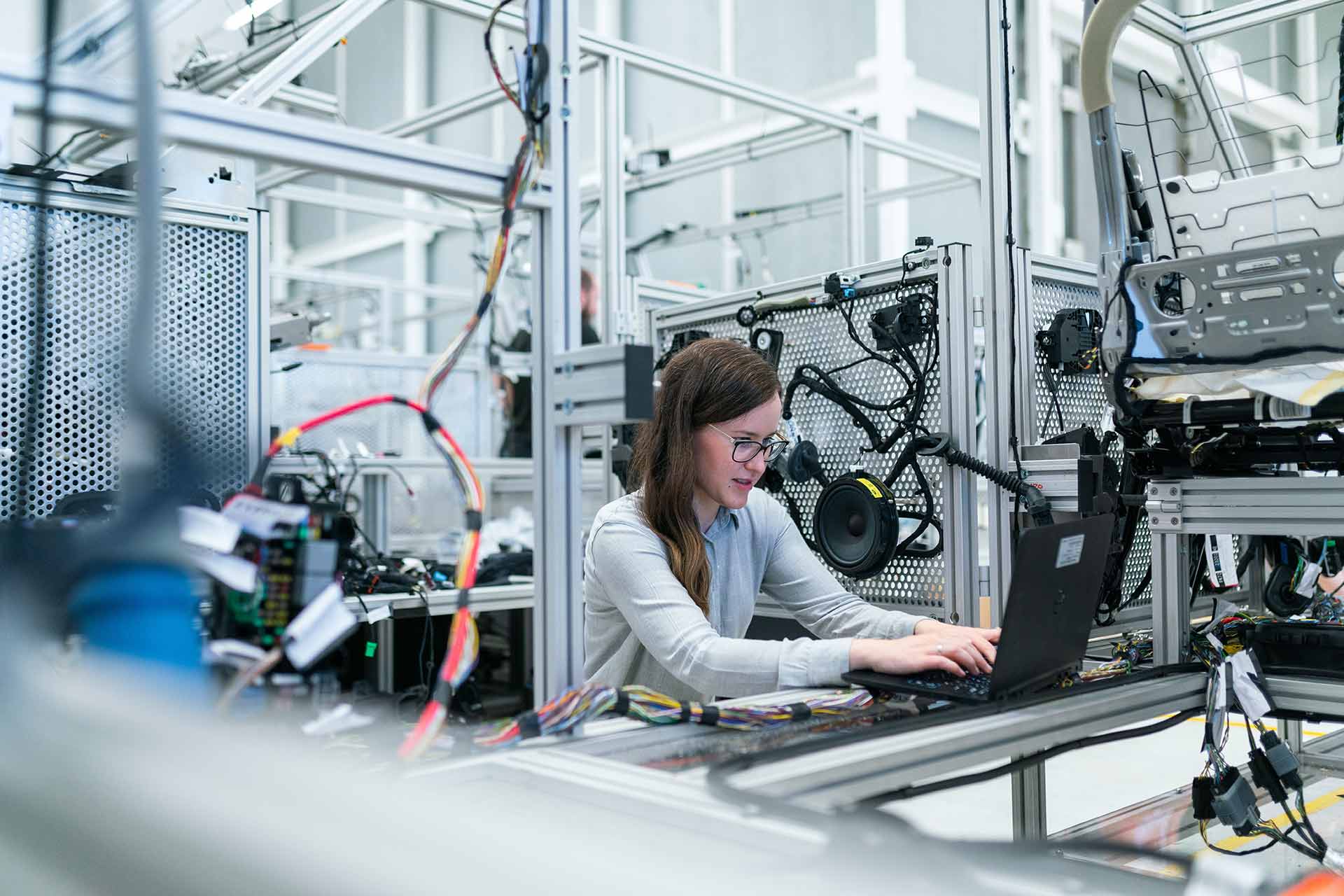 A woman working on a laptop in an industrial setting.