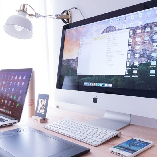 A desk with two computers and a phone on it