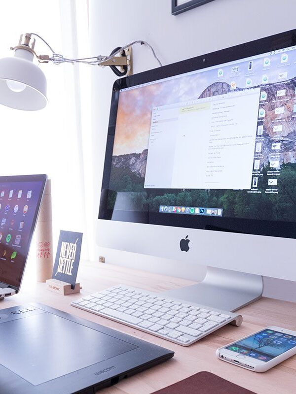 A desk with two computers and a phone on it