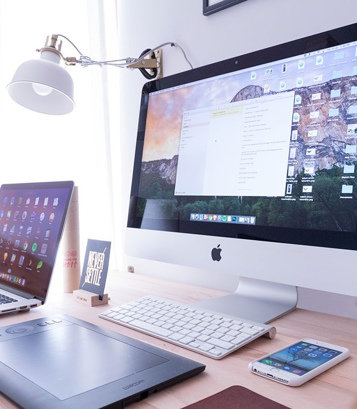 A desk with two computers and a phone on it