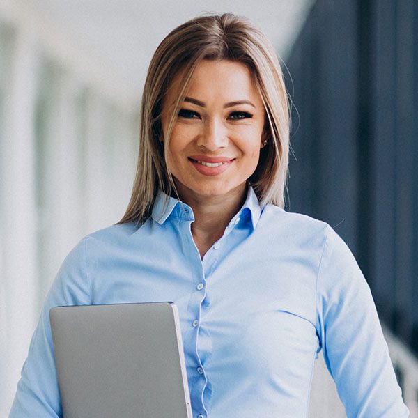 A woman in blue shirt holding a laptop.