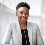 A woman in a white jacket smiling for the camera.