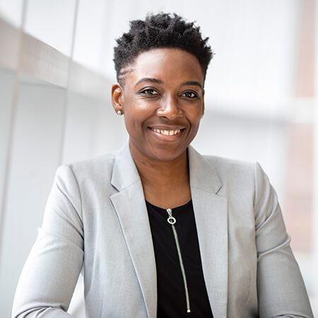 A woman in a white jacket smiling for the camera.