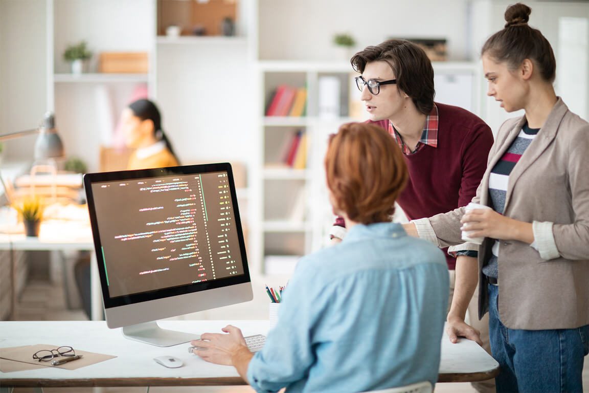 Three people are sitting at a table with computers.
