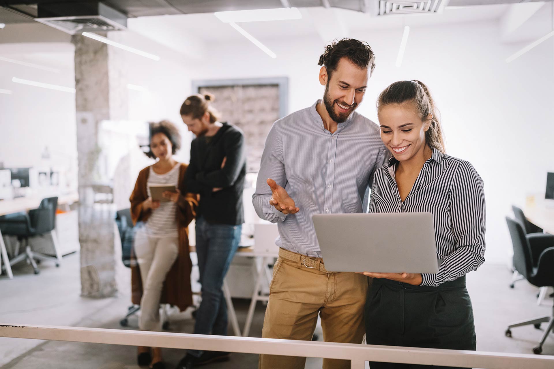Two people looking at a laptop in an office.