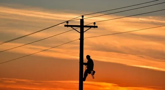 A man is climbing up to the top of a power pole.