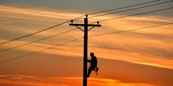 A man is climbing up to the top of a power pole.