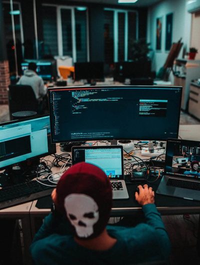 A person with a skull mask on sitting at a desk.